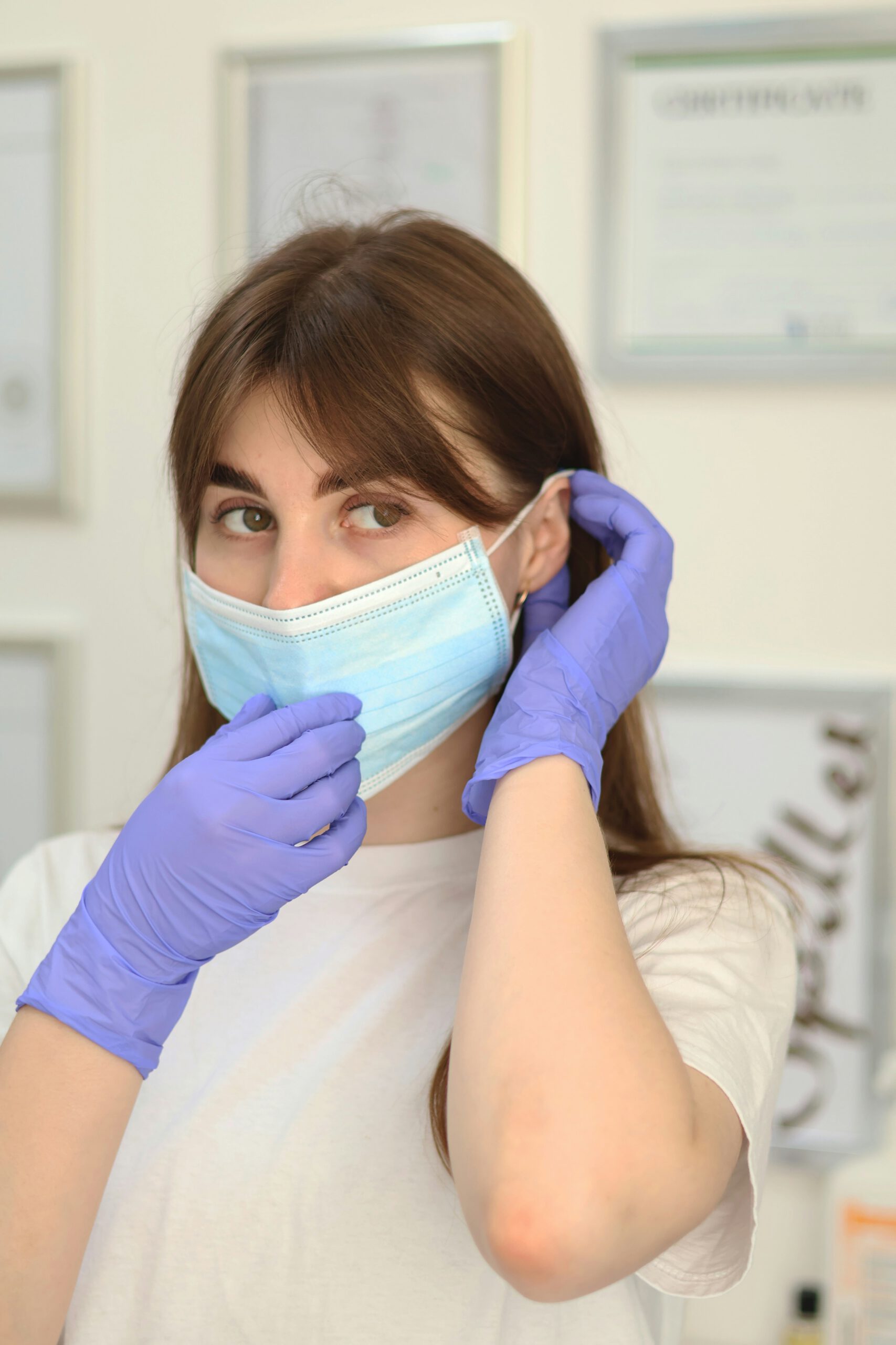 A woman wearing a surgical mask and gloves illustrating medical supplies