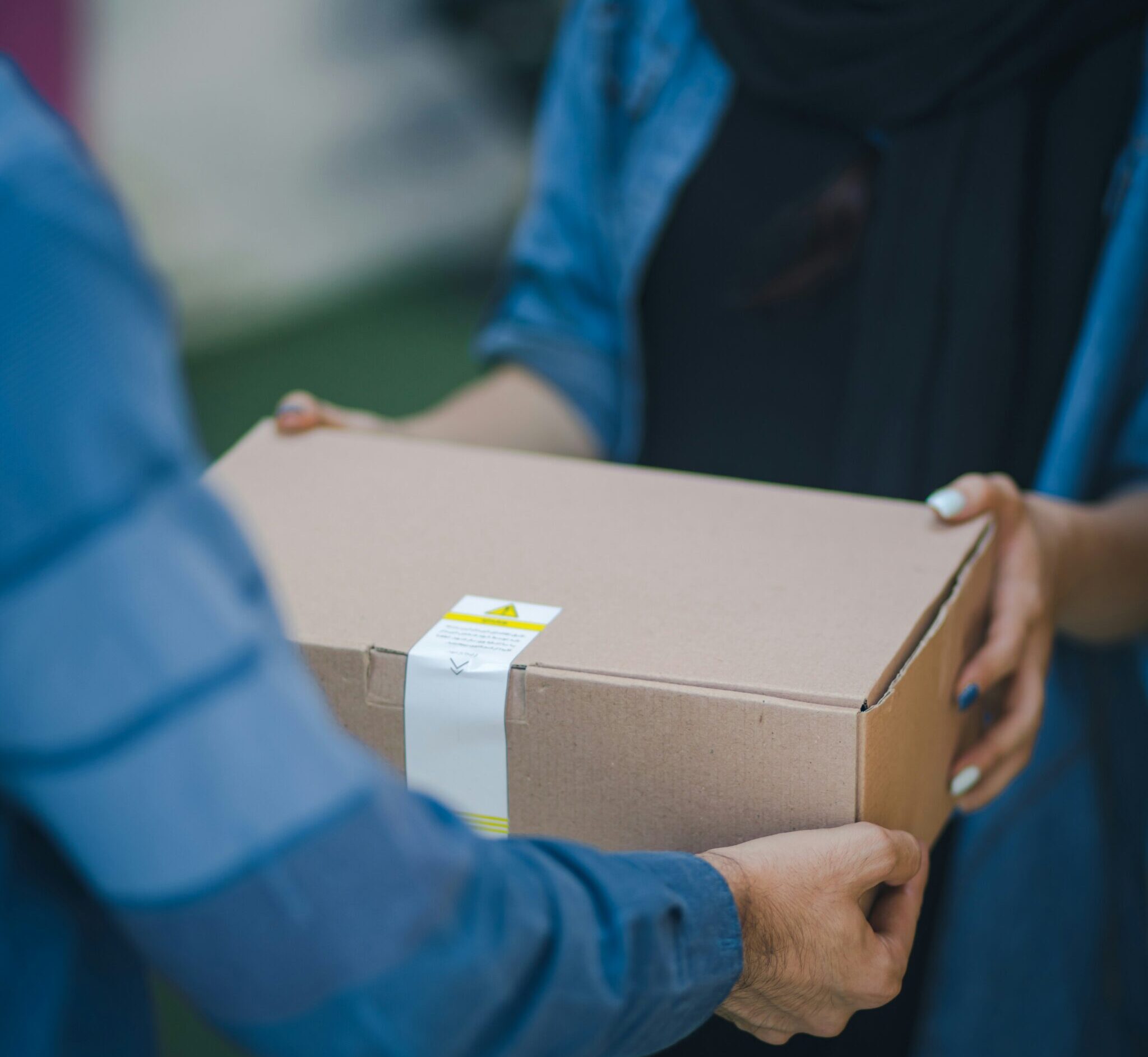 A box is passed from the hands of a delivery person to the recipient.